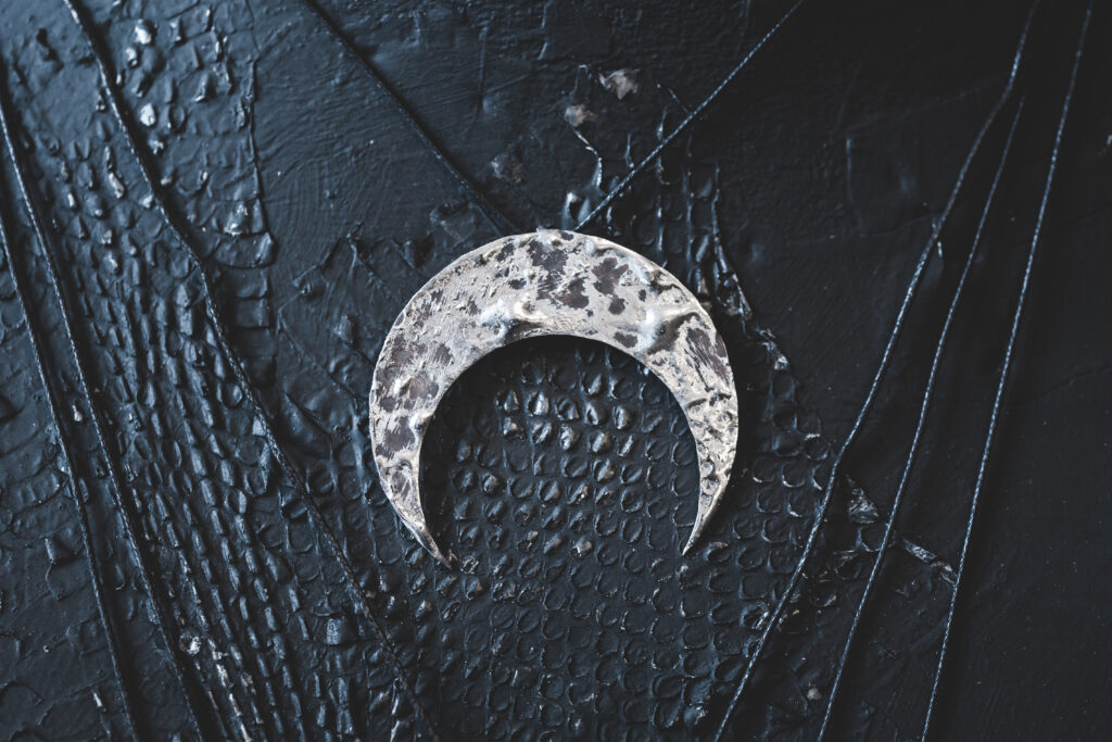 Silver female necklace in shape of Moon Crescent on a black background. The concept of magic and witchcraft.